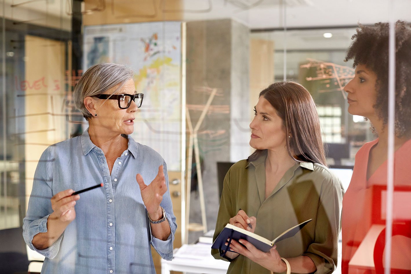 Businesswoman discussing with colleagues at glass