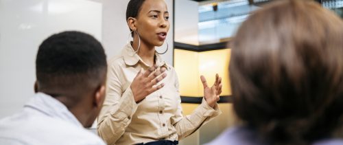 Young businesswoman explaining and gesturing in meeting black leader