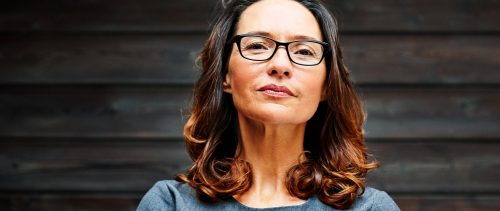 Mature businesswoman standing against a wooden wall in office