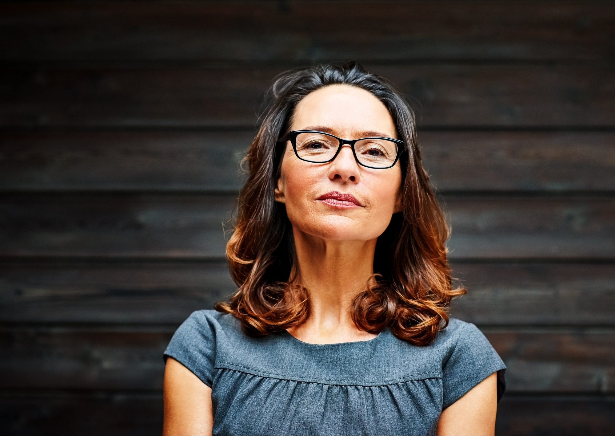 Mature businesswoman standing against a wooden wall in office