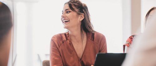 Cheerful businesswoman laughing at conference table
