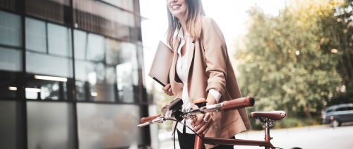 Young businesswoman standing on a city street with bicycle