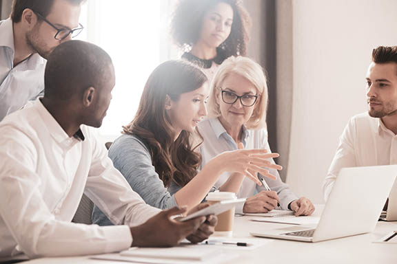 Female mentor teaching employees group analyzing online project explaining strategy