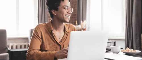 Joyful freelance worker sitting at laptop in home office