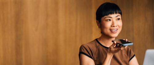 Woman Using Voice Command Technology on Smartphone in Office